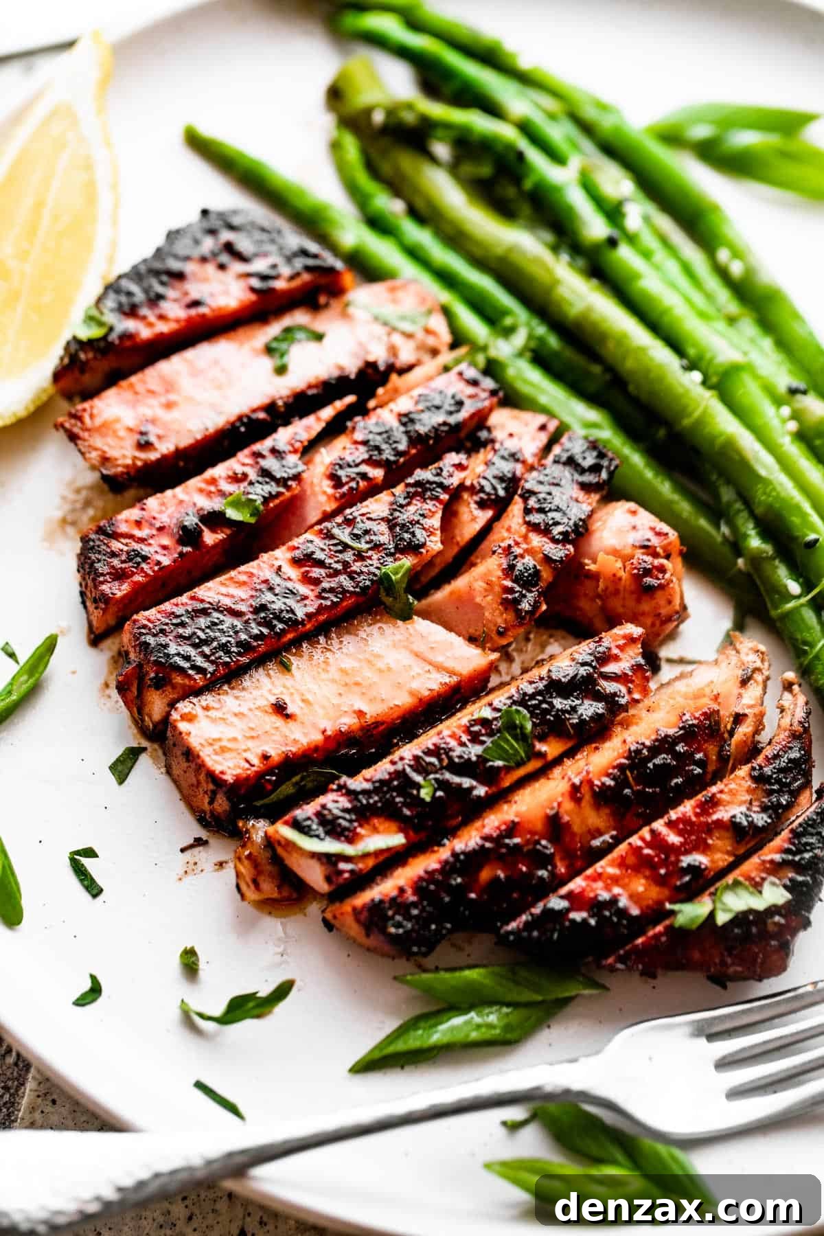 Enjoy a flavorful meal with this easy recipe for Blackened Balsamic Tuna Steaks, featuring a perfect blend of spicy Cajun spices and sweet balsamic vinaigrette. Overhead close-up shot of perfectly sliced blackened balsamic tuna served on a dinner plate with fresh asparagus stalks.