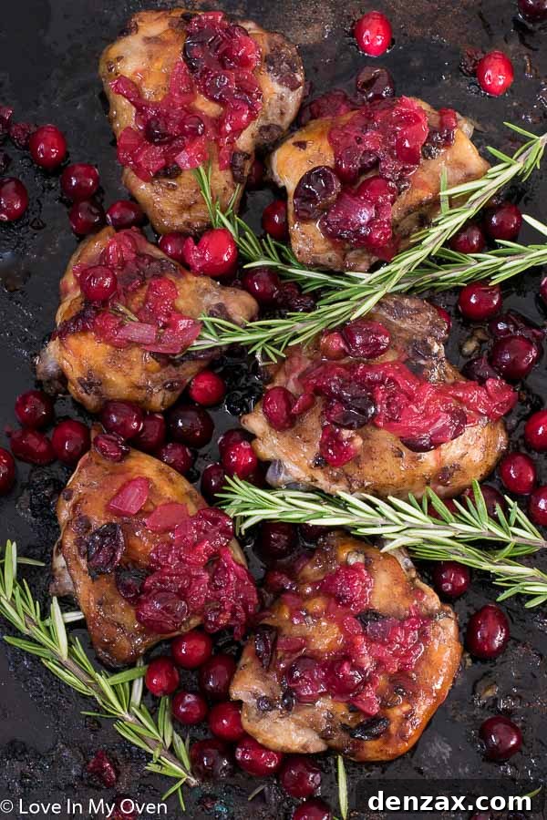 Cranberry Chicken Thighs with a simple cranberry glaze, garnished with fresh cranberries and herbs.