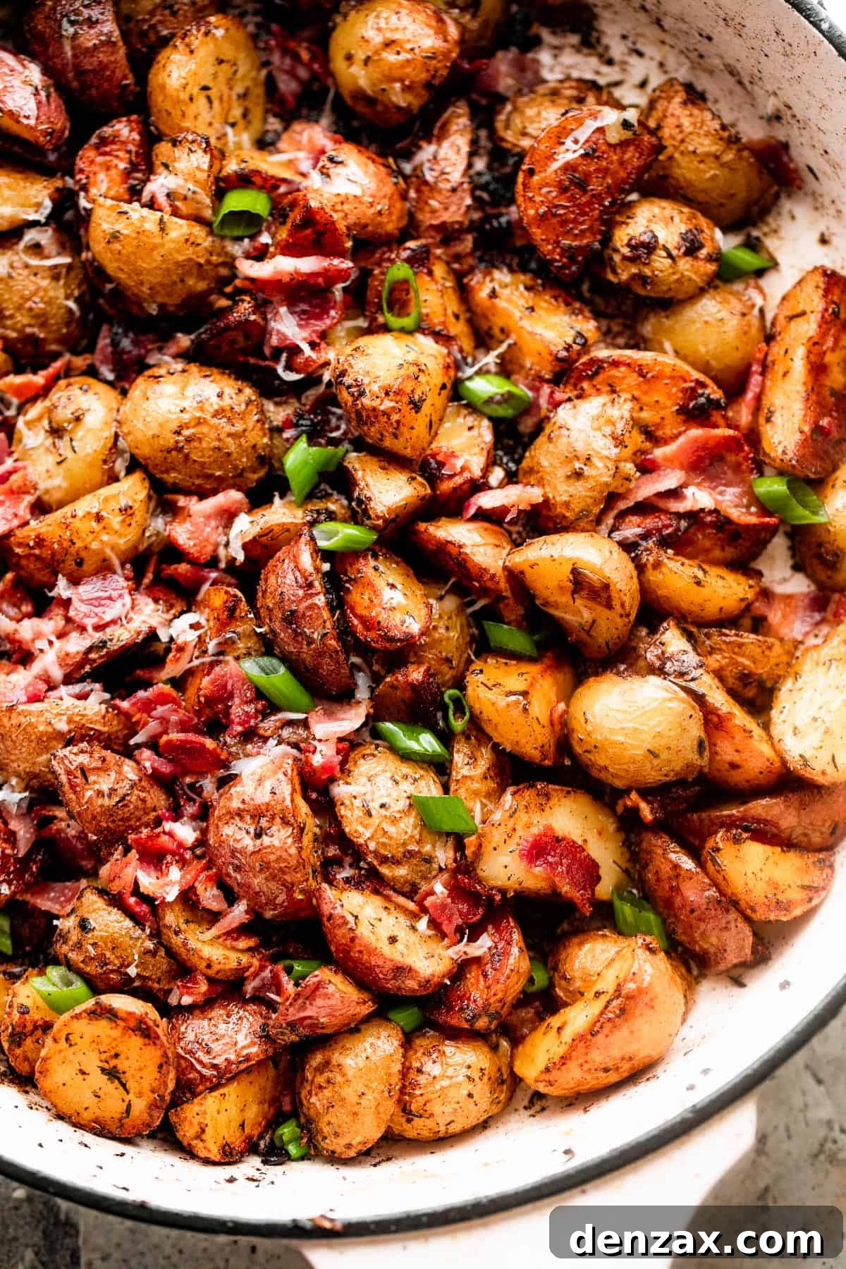 overhead shot of roasted potatoes and bacon in a white skillet, ready to be served.