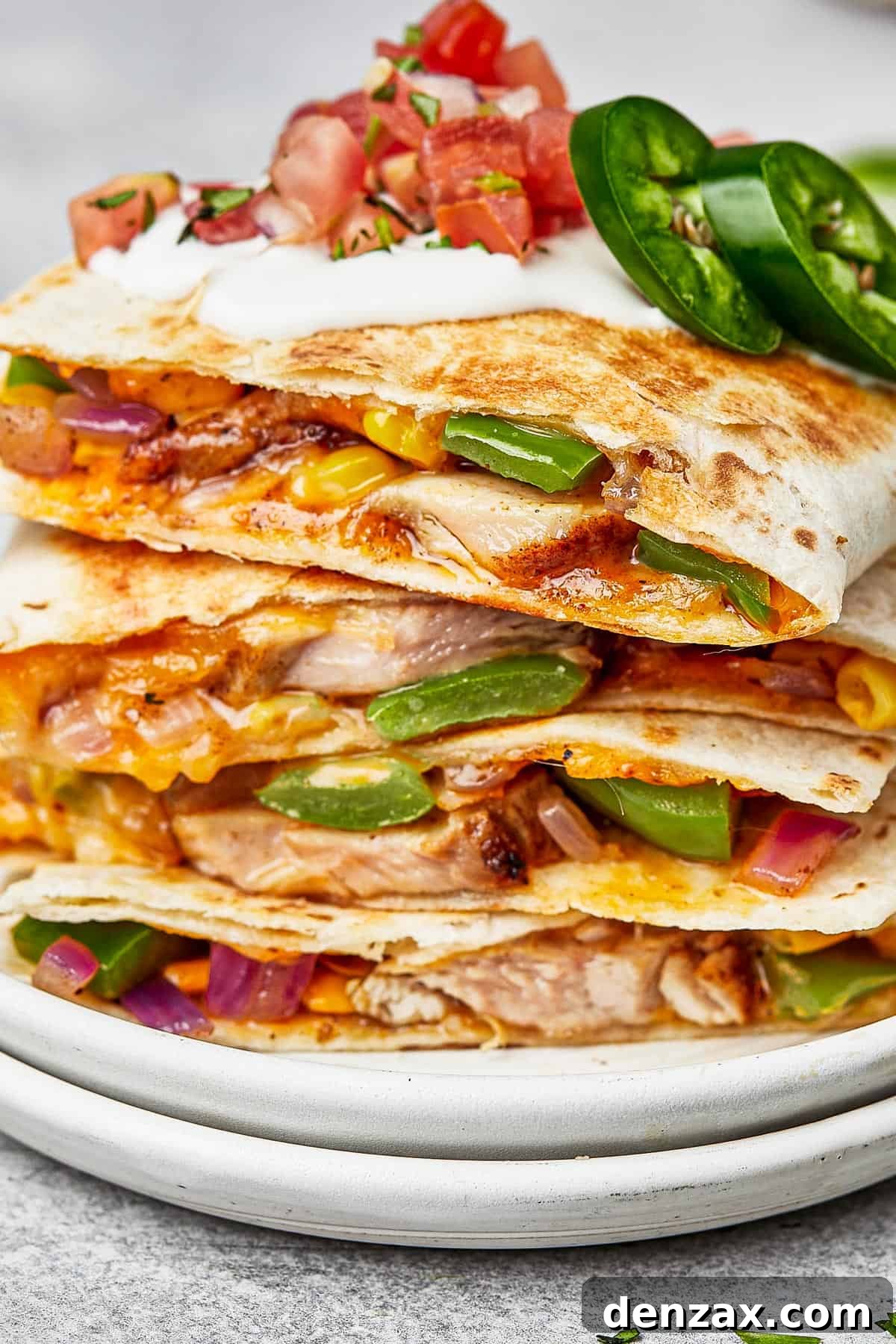 Stacked chicken quesadillas on a plate, showcasing their golden-brown tortillas and cheesy filling.