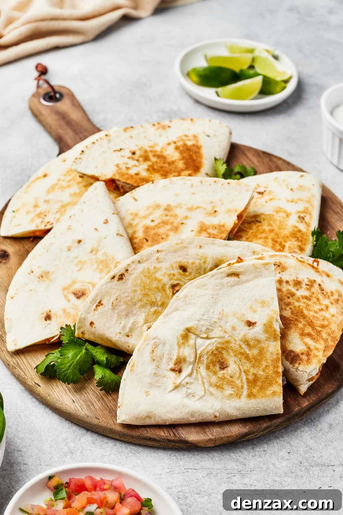 Golden-brown chicken quesadilla wedges fanned out on a rustic wooden board, garnished with fresh jalapeno slices.