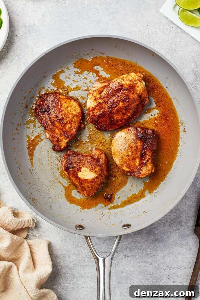 Boneless, skinless chicken thighs searing to golden perfection in a hot skillet.