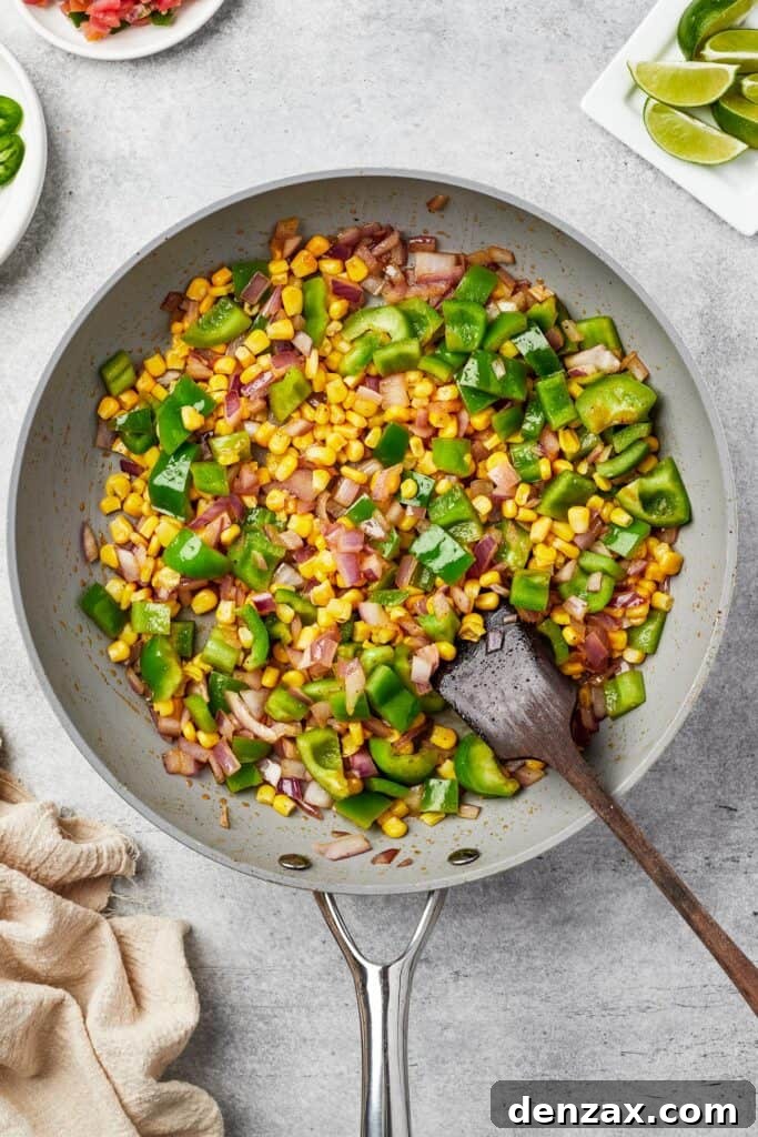 Vibrant bell peppers, red onions, and corn kernels sautéing in a skillet, becoming tender-crisp.