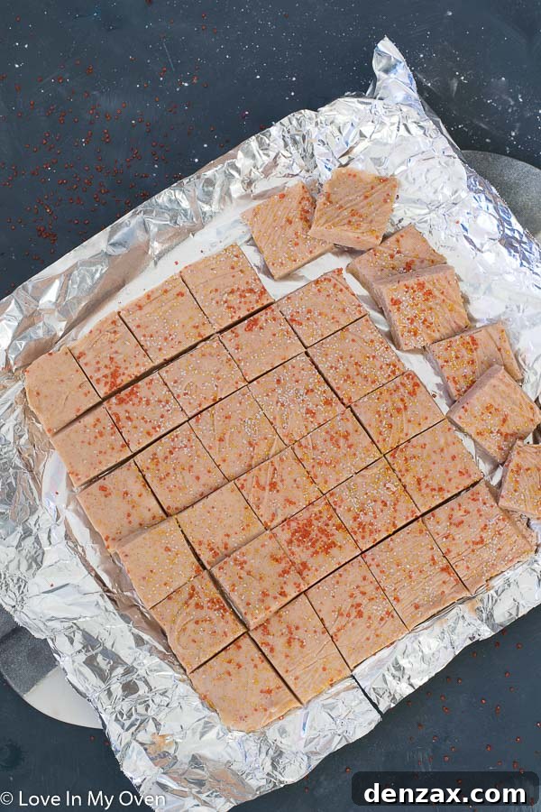 Hand holding a square of gingerbread fudge, showcasing its rich, dense texture and perfect shape.