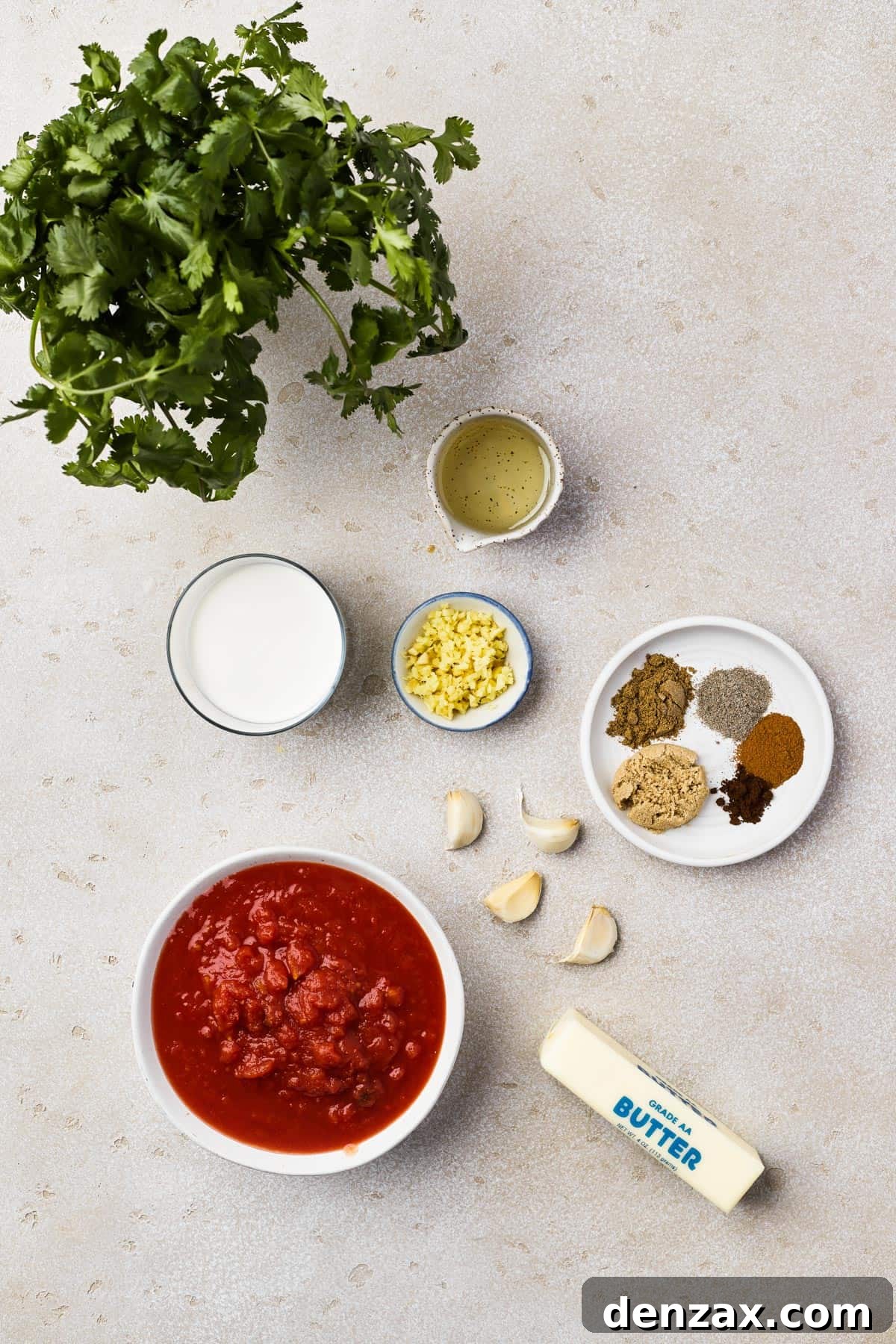 Butter Chicken Makhani 5 A flat lay of ingredients for butter chicken: cilantro, oil, cream, ginger, spices, garlic, tomatoes, butter.