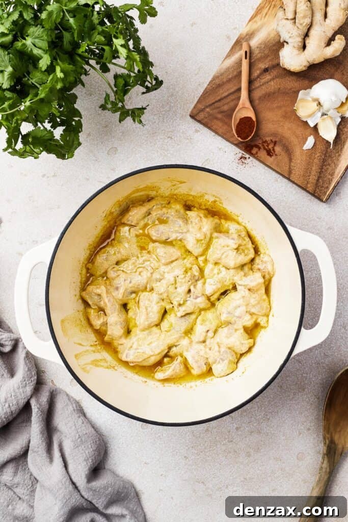 Butter Chicken Makhani 7 Marinated chicken cooking in a pan, forming a light yellow sauce.