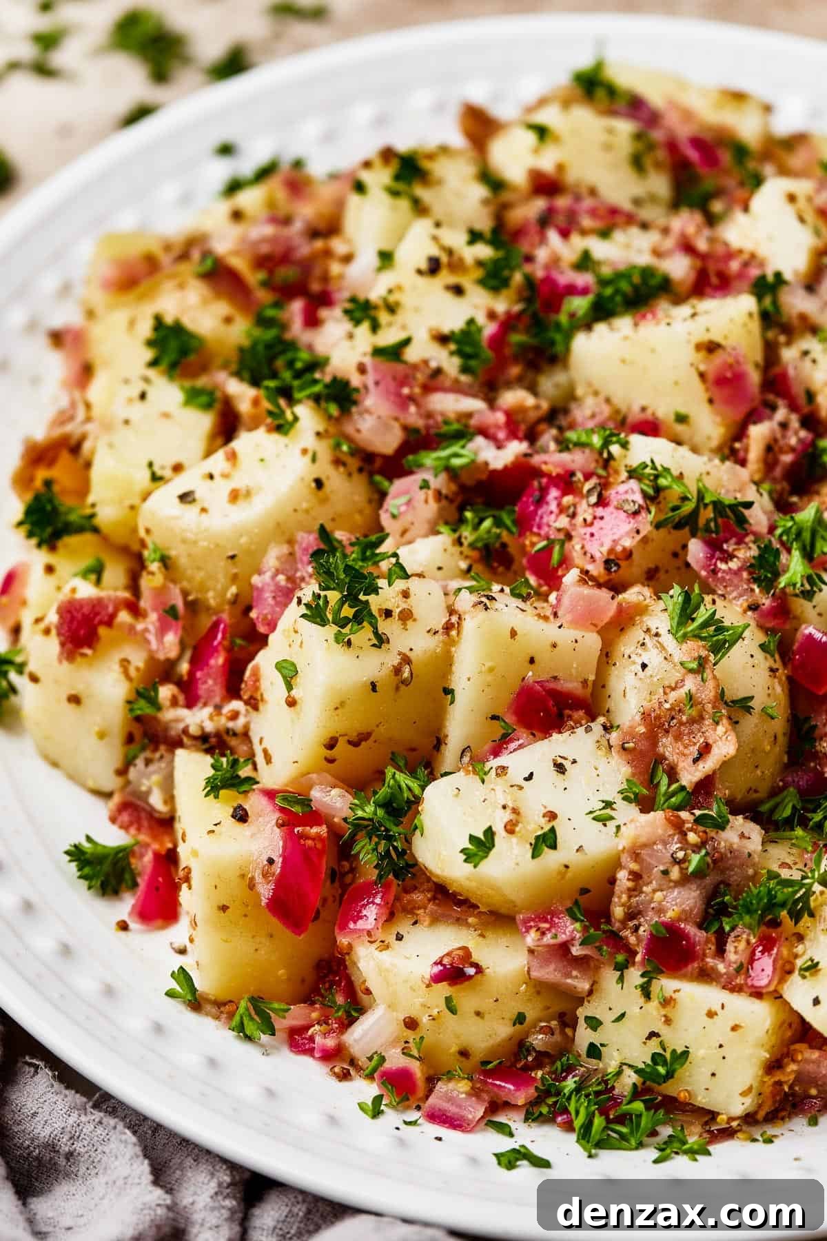 Close-up shot of chopped, boiled potatoes tossed with crispy bacon and a vibrant dressing.