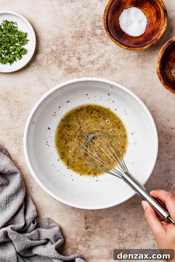 Vinaigrette ingredients being whisked together in a bowl, showing the preparation of the tangy dressing.