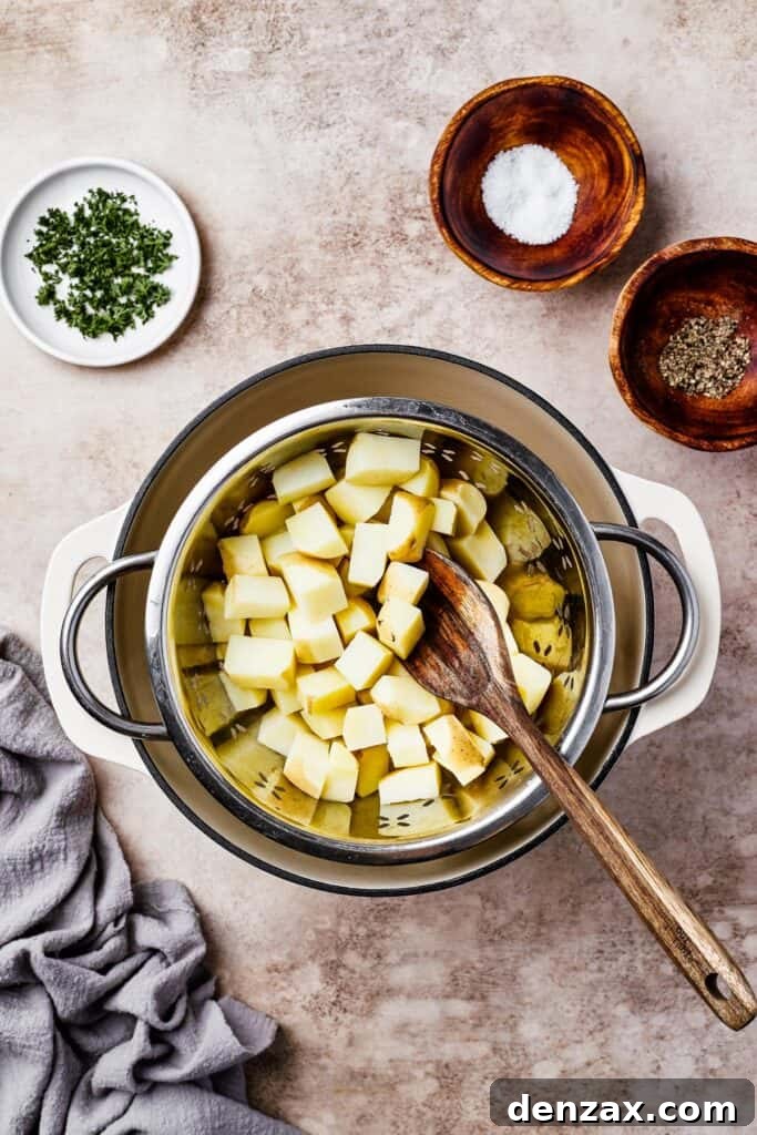 Potatoes boiling in a large pot on the stove, with small dishes of parsley, salt, and pepper arranged on the counter.