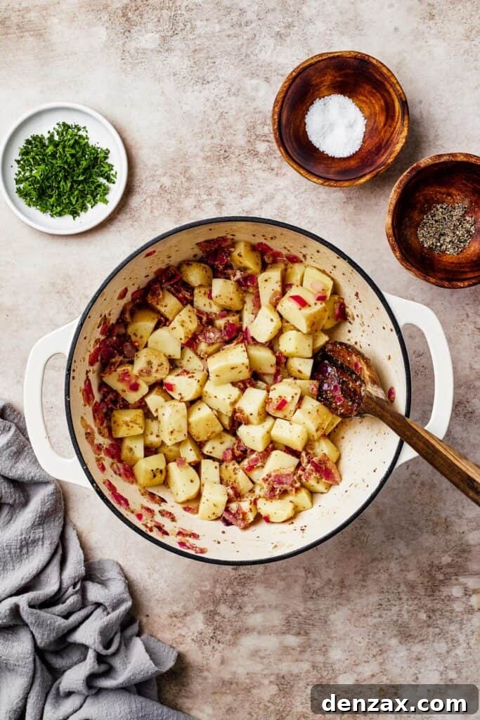 Potatoes gently mixed with crispy bacon and the warm vinaigrette dressing in a large pot, evenly coated and ready to rest.