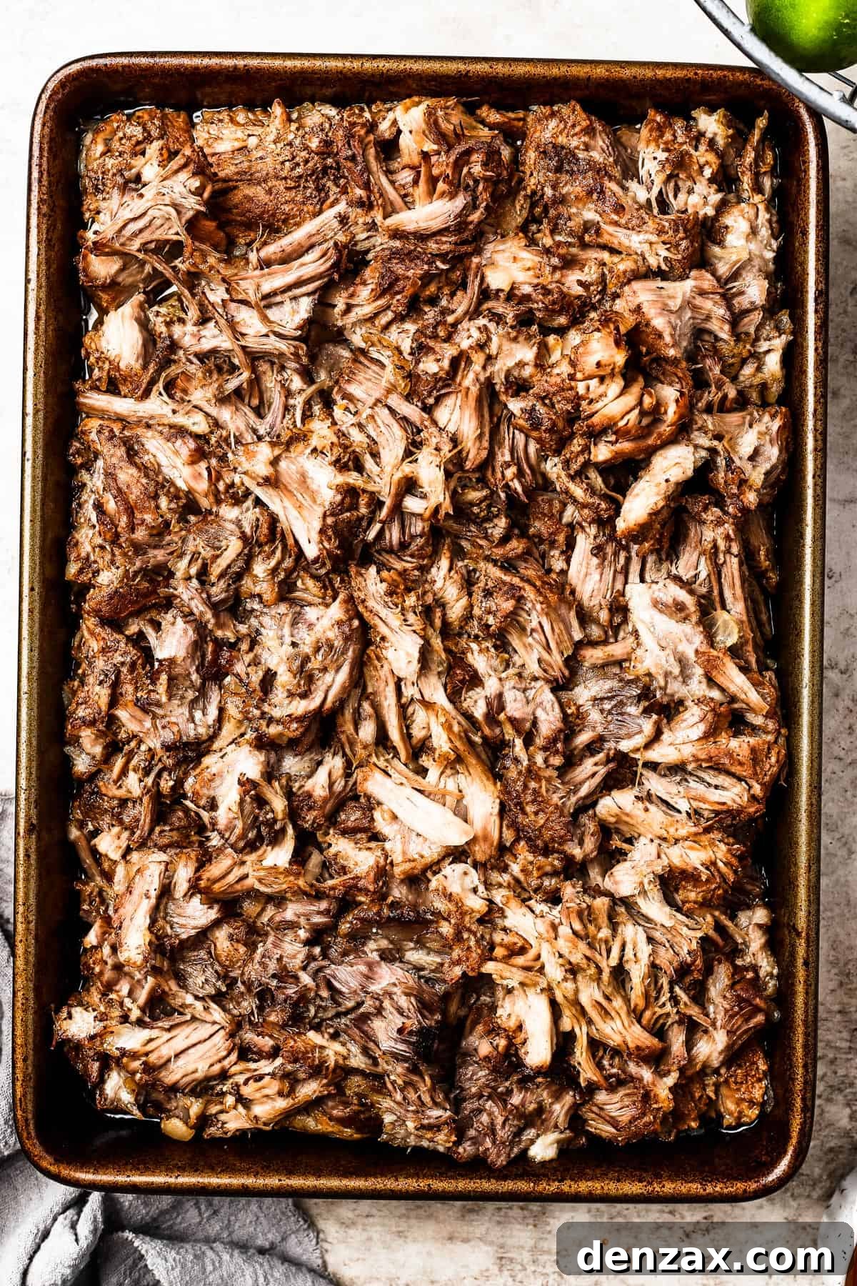 Browned shredded pork spread in a thin layer on a baking sheet, fresh out of the broiler.