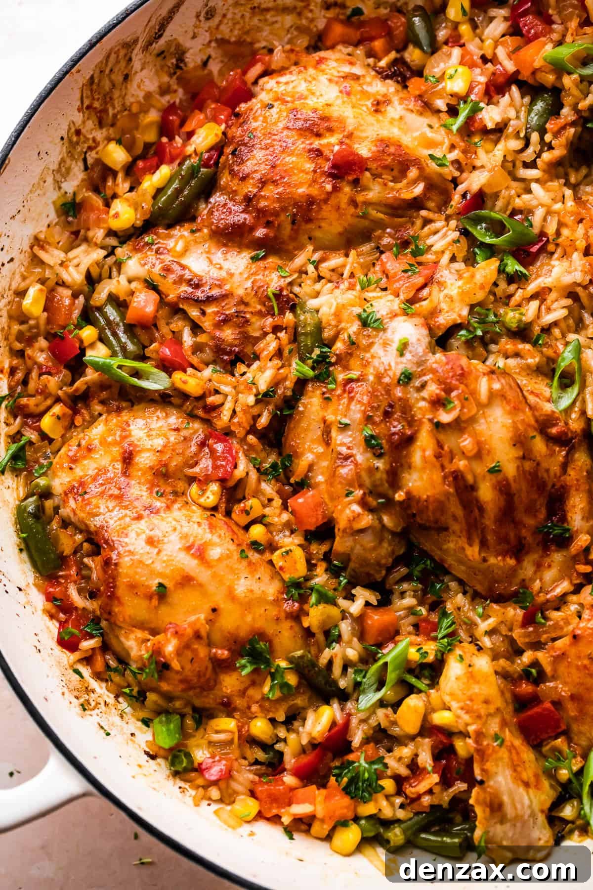 Overhead shot of a round casserole dish featuring perfectly cooked ranch chicken thighs, fluffy rice, and a vibrant mix of vegetables.