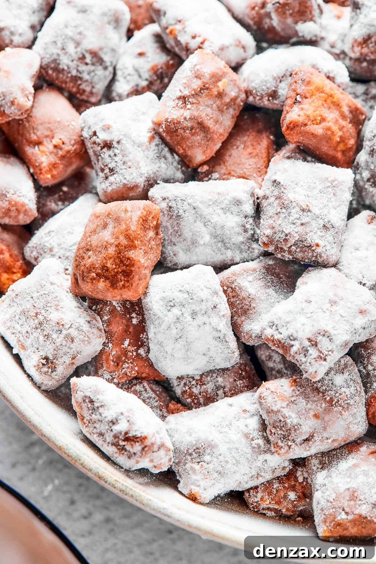 Puppy Chow 11 Close-up shot of puppy chow in a white bowl, to show the texture. Some pieces are fully coated in powdered sugar, while others are not.