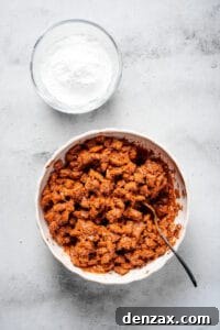 Puppy Chow 8 Chex cereal coated in chocolate and peanut butter, with a bowl of powdered sugar nearby.