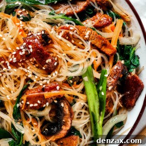 overhead shot of a shallow dish of beef noodle stir fry, garnished with sesame seeds.