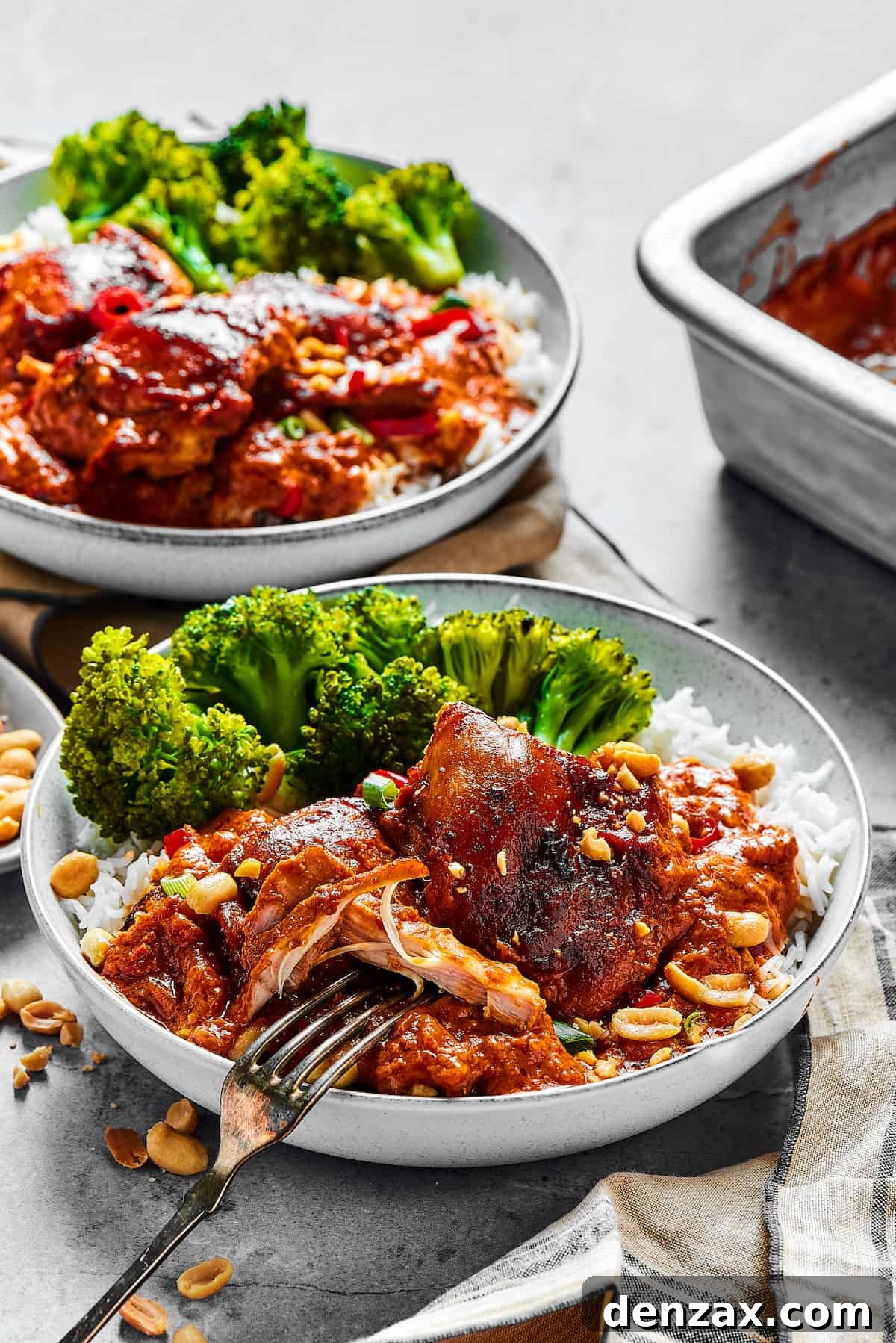 Two plates of saucy chicken and veggies.