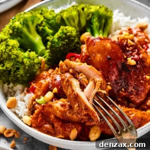 A close-up shot of a chicken thigh cooked in peanut sauce, with a fork pulling away a bite.