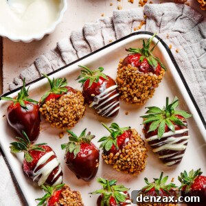 A white tray with a black border, displaying three kinds of chocolate dipped strawberries: plain, white chocolate drizzle, and toasted hazelnuts.