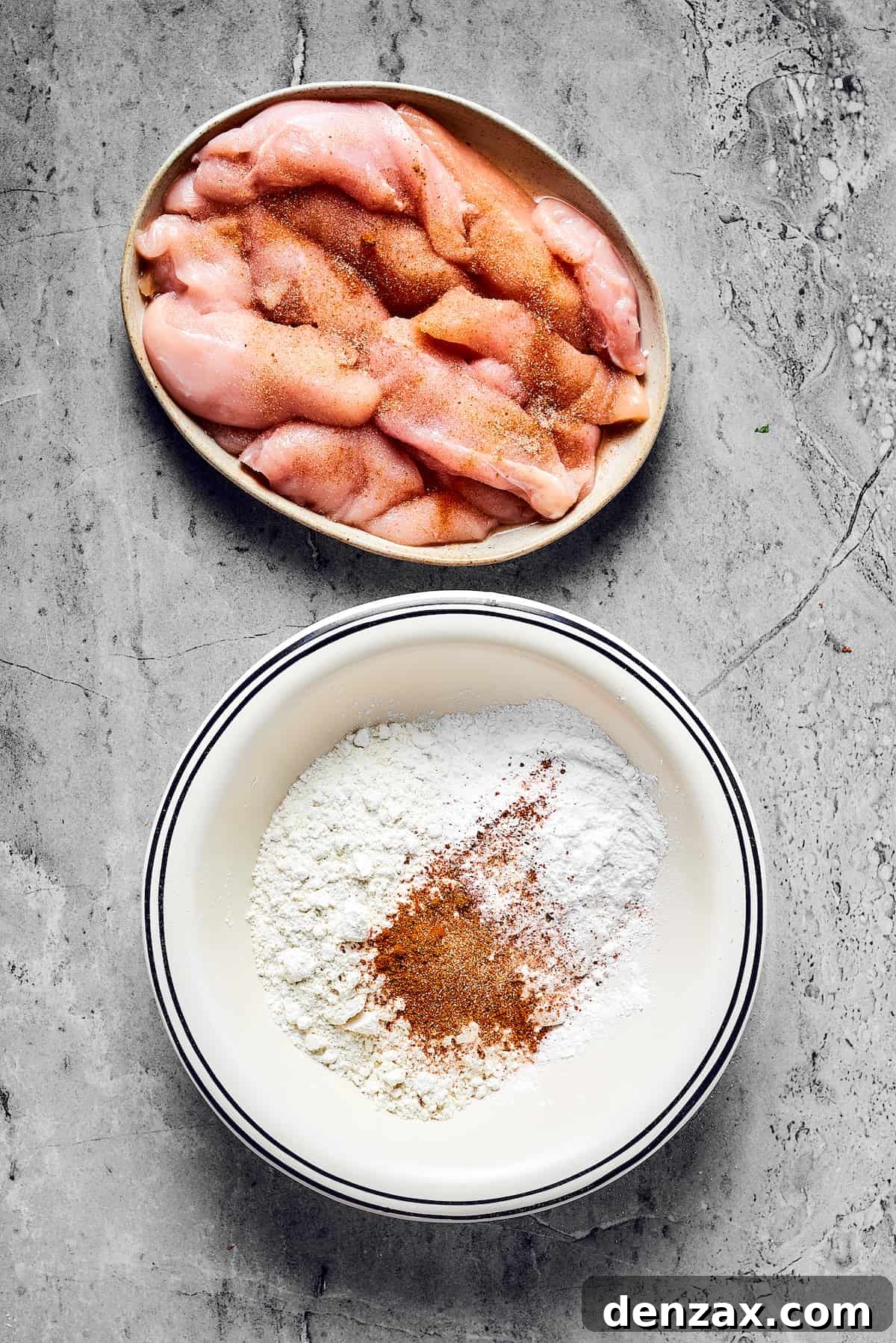 A dish of raw, perfectly seasoned chicken strips sits beside a bowl of seasoned flour, illustrating the first steps of the preparation process for Air Fryer Chicken Tempura.