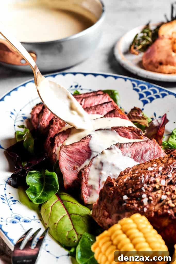 Sliced blue steak with creamy blue cheese sauce being elegantly spooned over each tender piece, ready to be served.