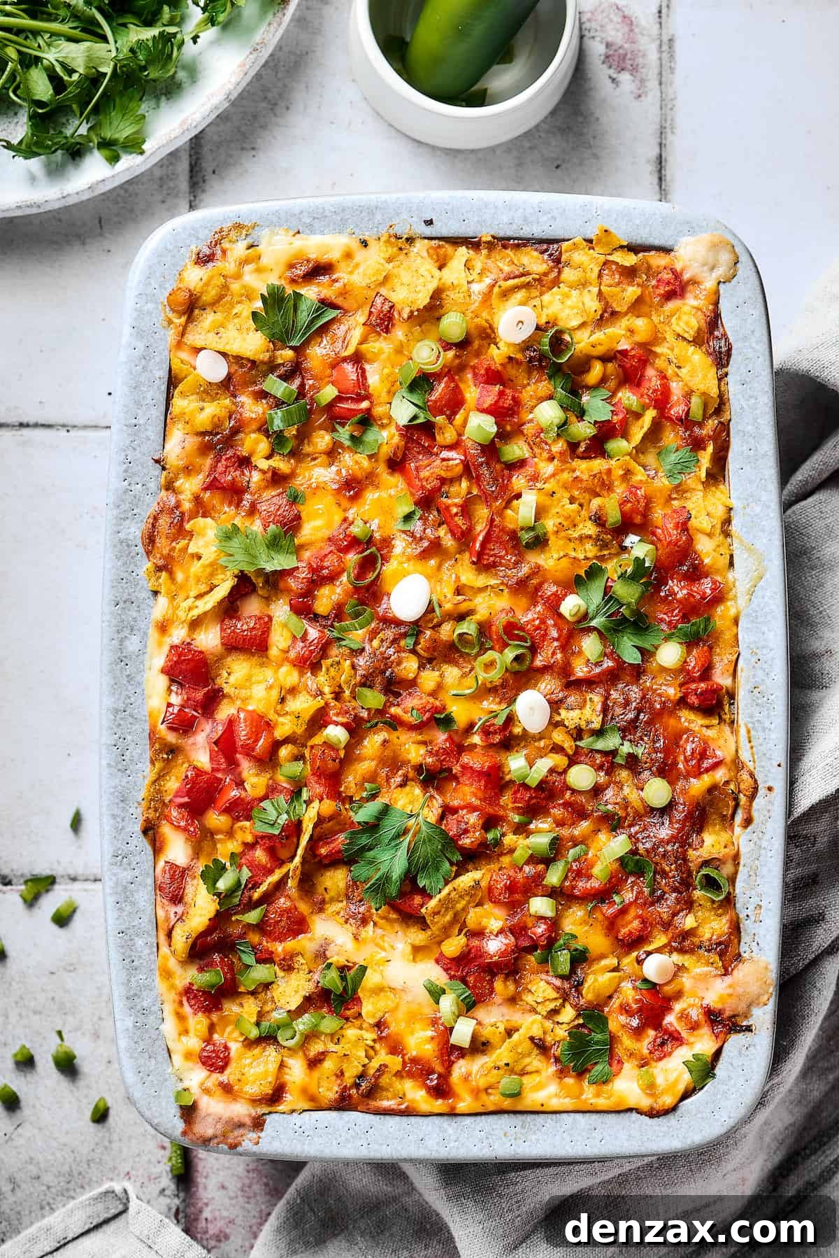 A baked chicken casserole garnished with cilantro, green onion, and jalapeno.