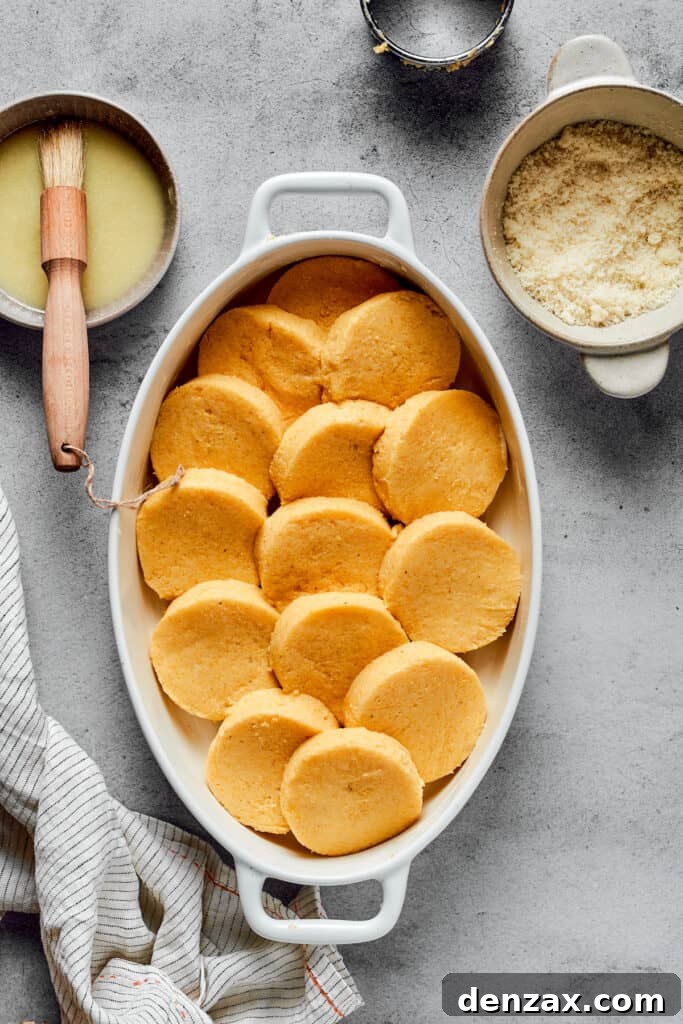 Circular semolina gnocchi layered into an oval baking dish.