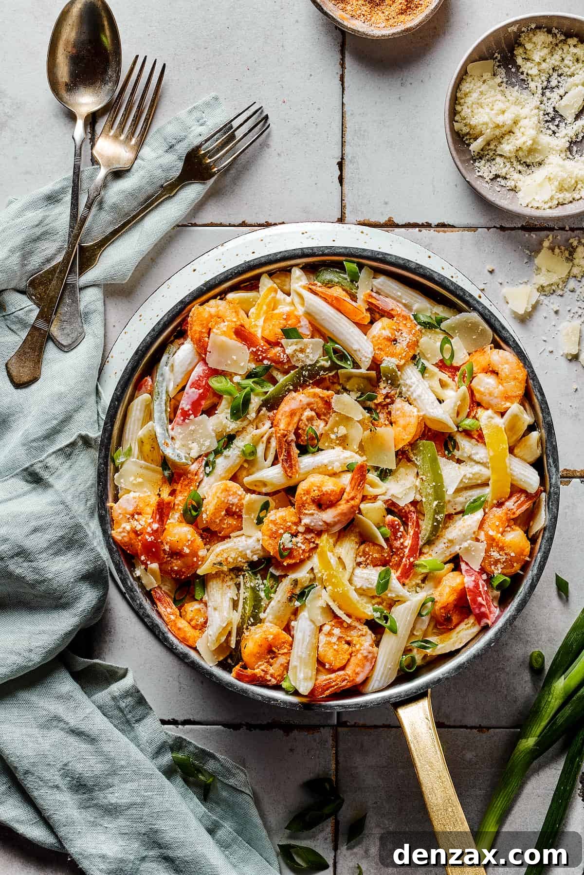 A skillet of Rasta Pasta served with cutlery and a cloth napkin, ready for a family meal.