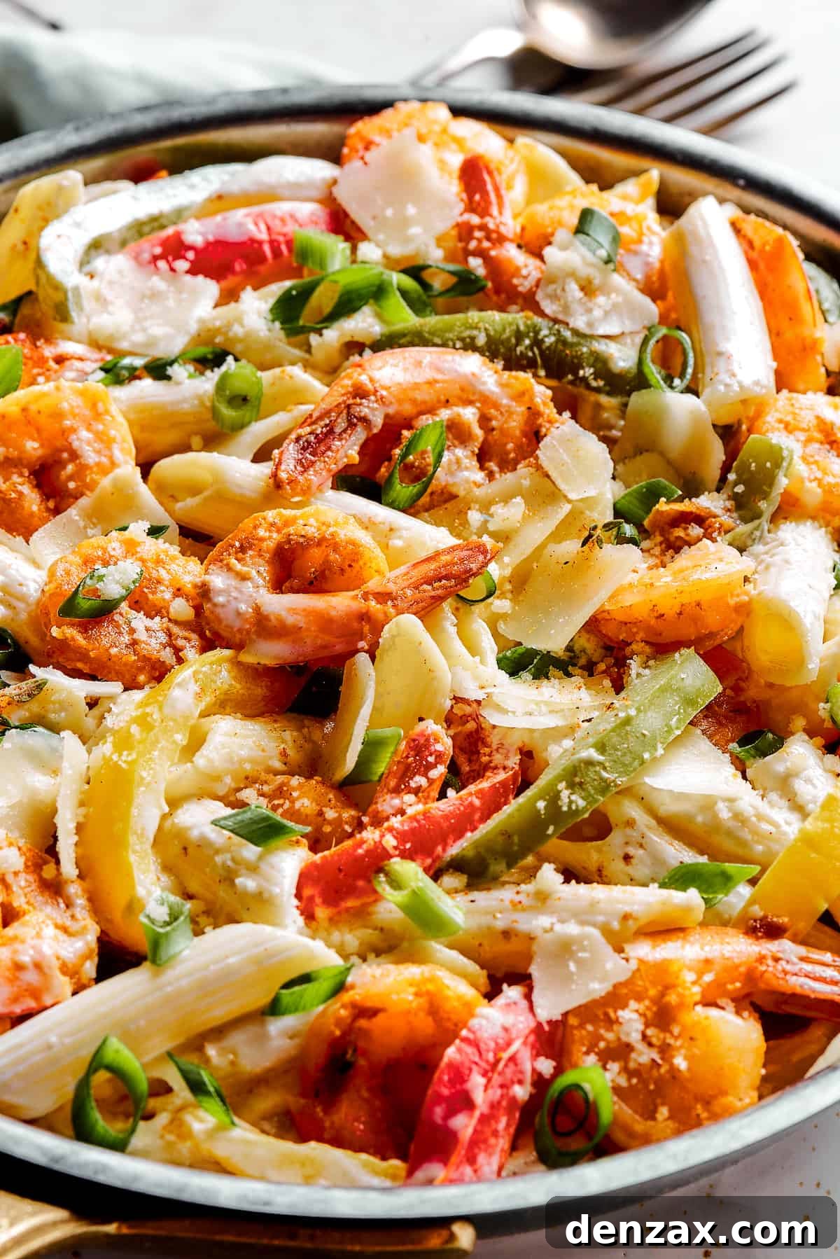 A skillet of bell peppers, pasta, and spicy shrimp in a creamy sauce, ready to be served.