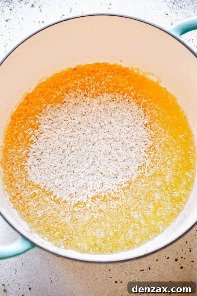 dutch oven with raw rice frying in butter