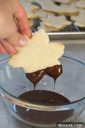 Decadent Chocolate Dipped Shortbread 7 Chocolate-dipped shortbread cookie being carefully placed on parchment paper for topping.