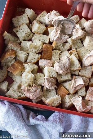 Adding remaining bread cubes over cream cheese layer for overnight French toast