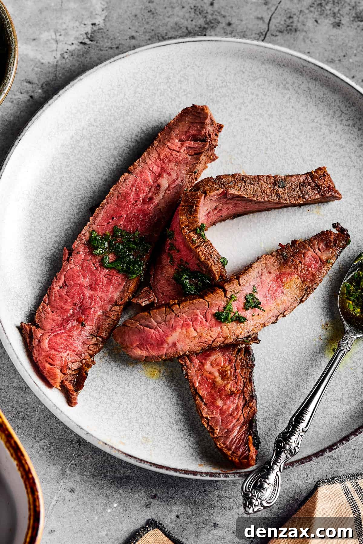 Appetizing medium-rare steak slices arranged on a small plate, delicately drizzled with a flavorful sauce.