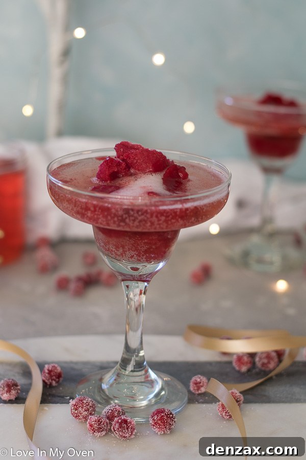Cranberry Sorbet Champagne Float in a flute glass with fresh cranberries and a sprig of rosemary.