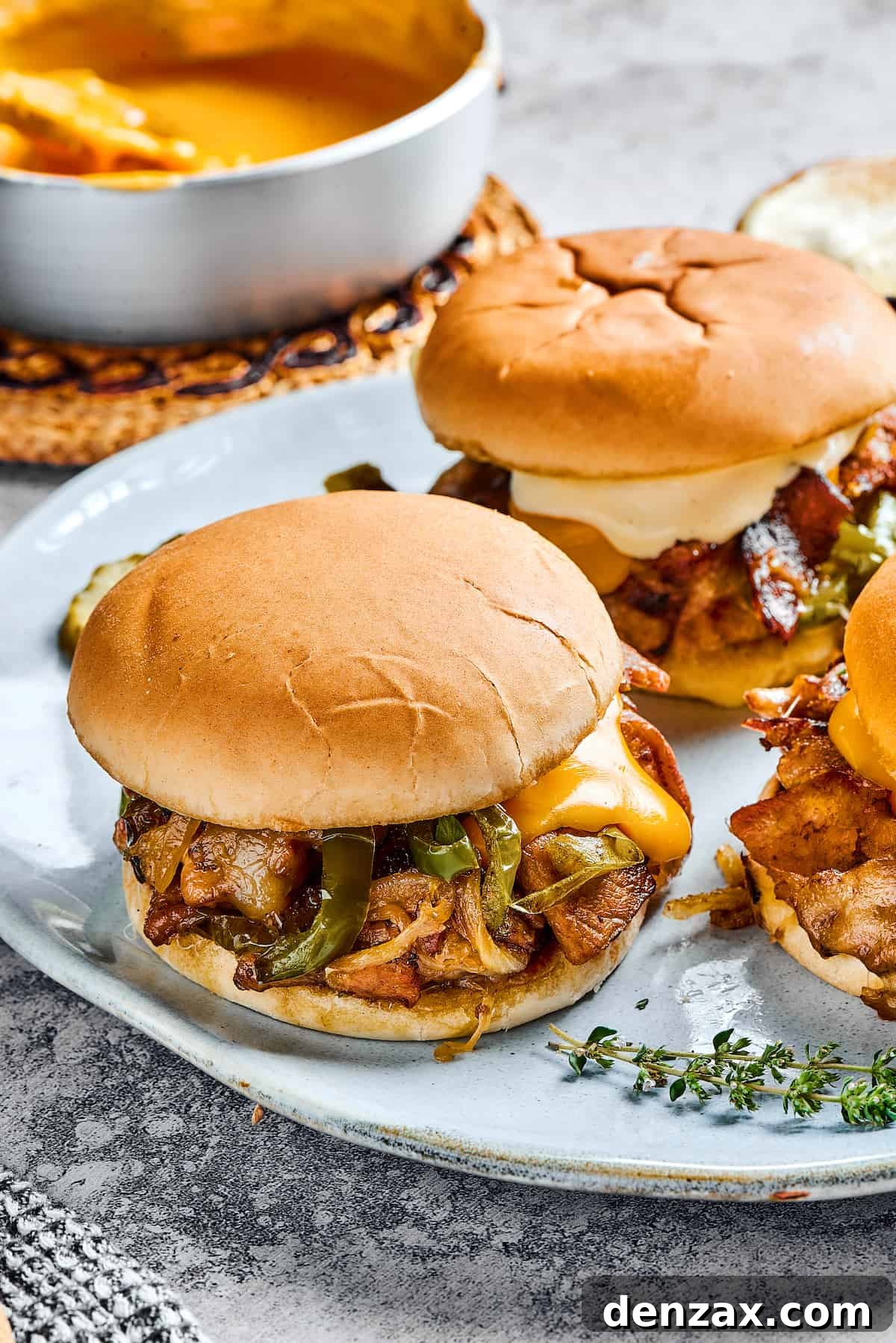Two mouth-watering steak sandwiches, bursting with sautéed onions, green bell peppers, and richly melted cheese, ready to be enjoyed.