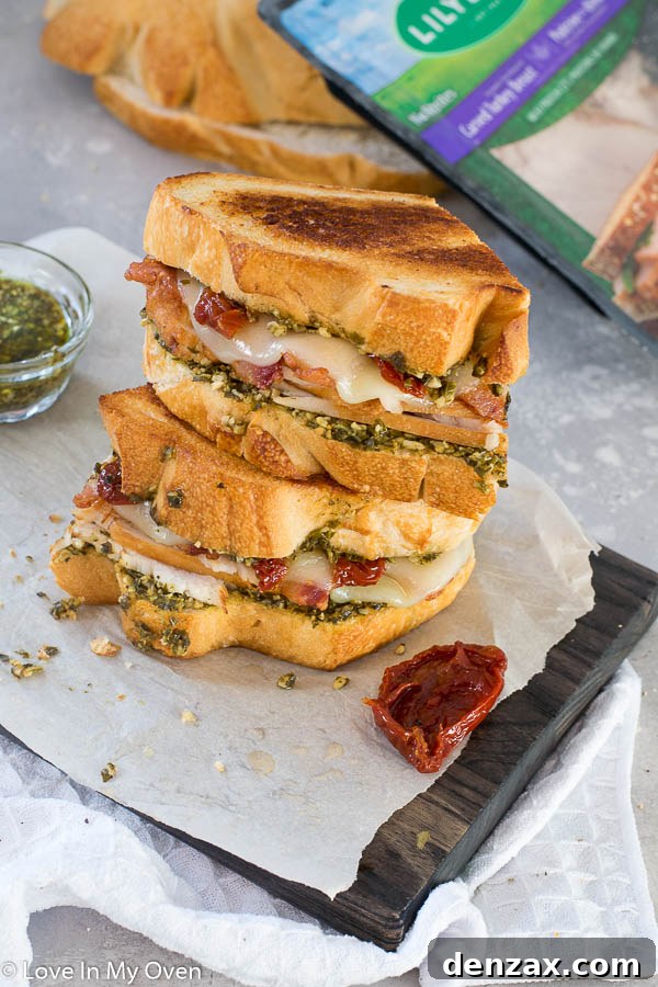 Two halves of a delicious turkey pesto sandwich on a plate