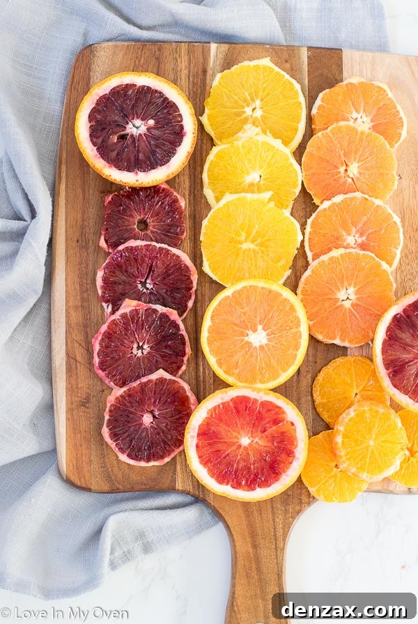 A close-up of various citrus slices, including blood oranges, cara cara, and navel oranges, arranged for a colorful upside down cake.