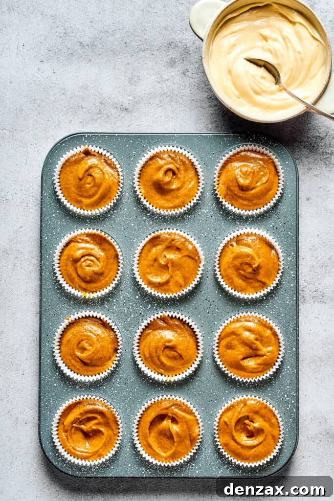 A muffin tin with muffin batter poured into paper liners.