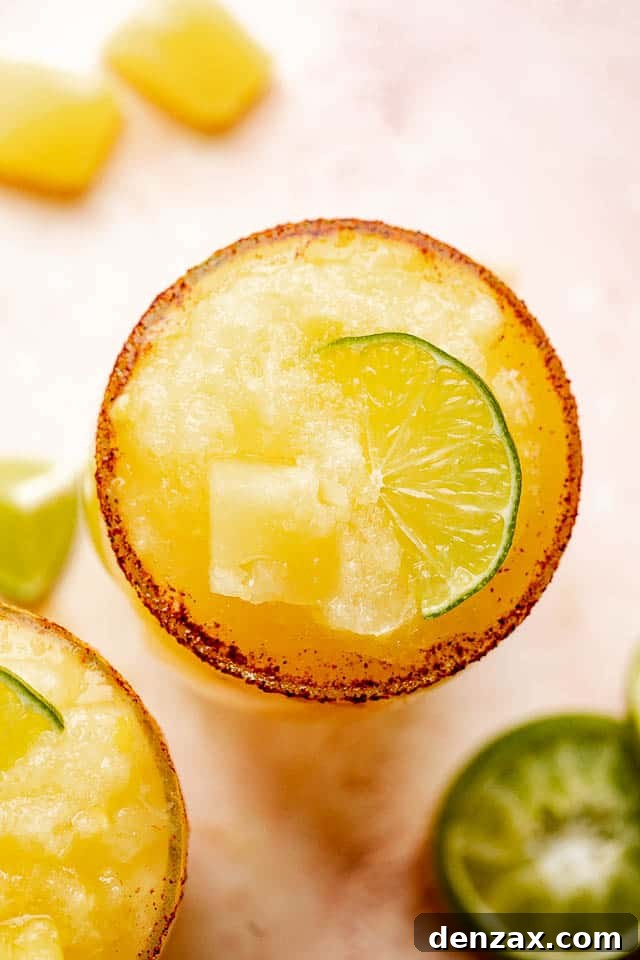 Close-up top view of a frozen pineapple margarita glass showing the slushy texture and chili-salt rim.