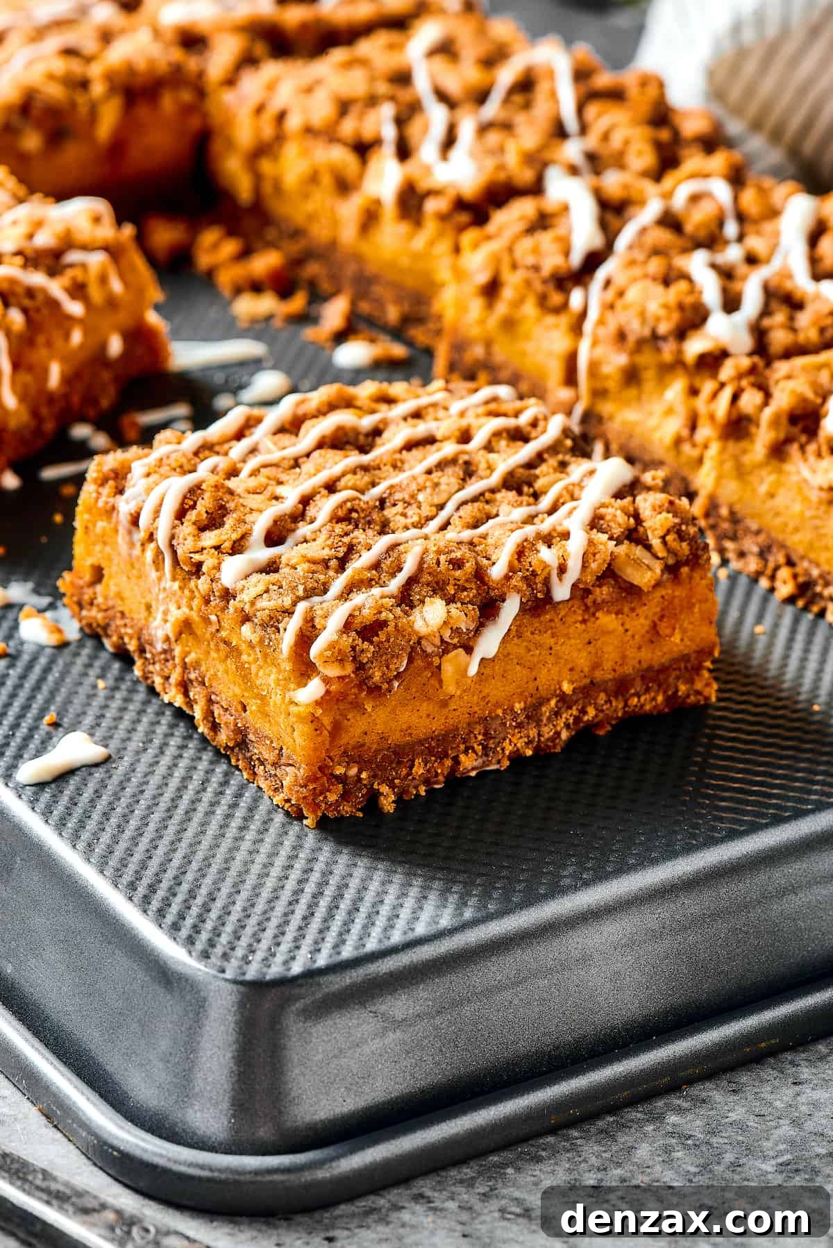 Pumpkin bars drizzled with cream cheese topping, showcasing the layered texture.