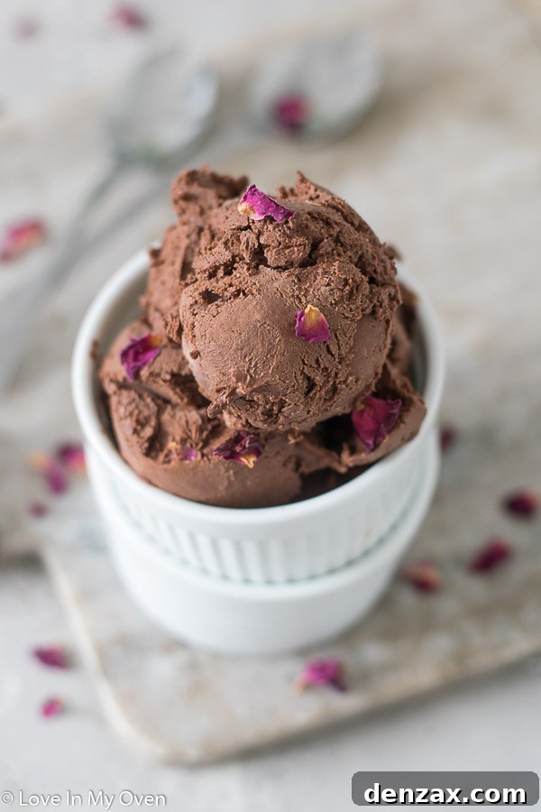 Three scoops of vegan chocolate ice cream in a white bowl, showing its creamy texture