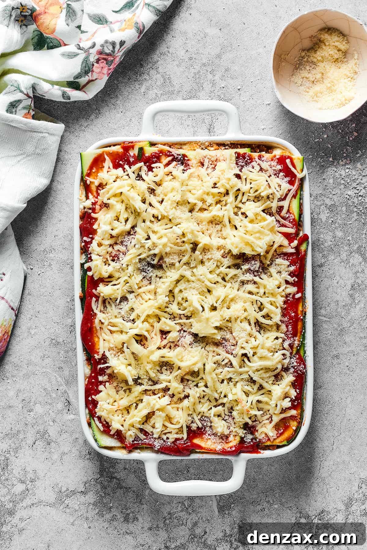 A vibrant, unbaked zucchini lasagna, beautifully topped with a generous layer of shredded mozzarella, ready to be transformed in the oven.