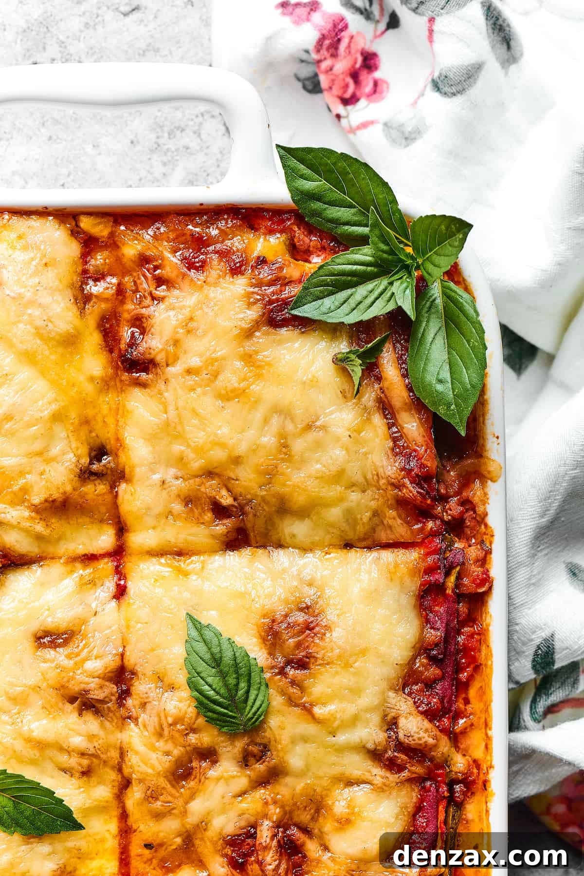 Close-up view of a perfectly baked Zucchini Lasagna slice, generously garnished with vibrant fresh basil, highlighting the rich meat sauce and melted cheese layers.