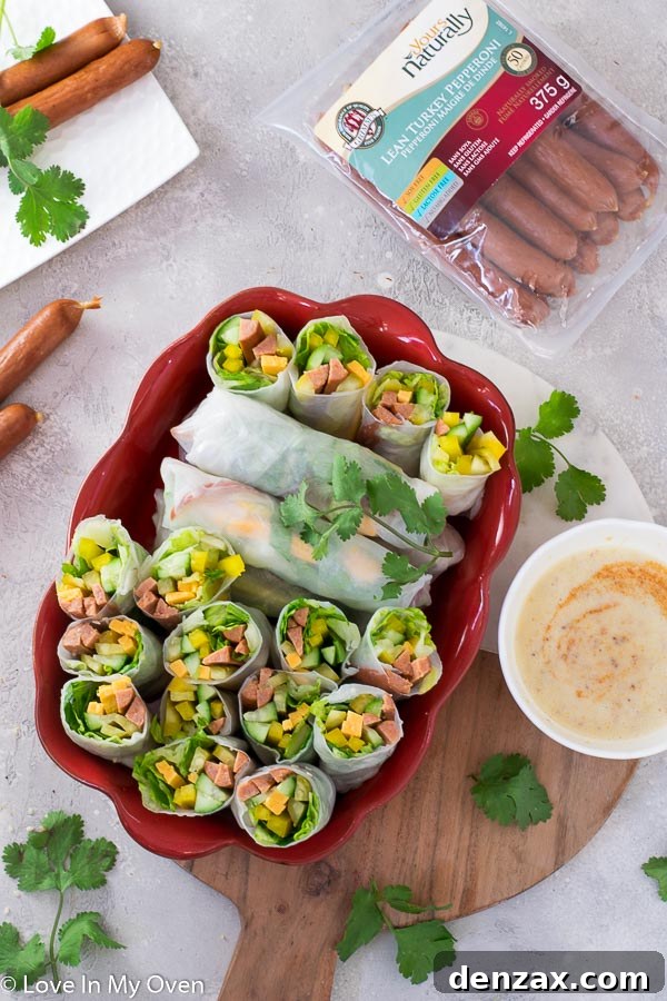 Delicious and healthy turkey pepperoni salad rolls arranged on a wooden board with dipping sauce, perfect for kids' parties or lunchboxes.