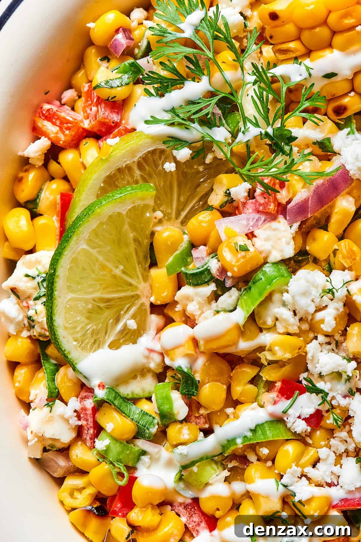 Close-up shot of Mexican street corn salad, showing the vibrant texture of the grilled corn kernels, chopped vegetables, and creamy dressing.
