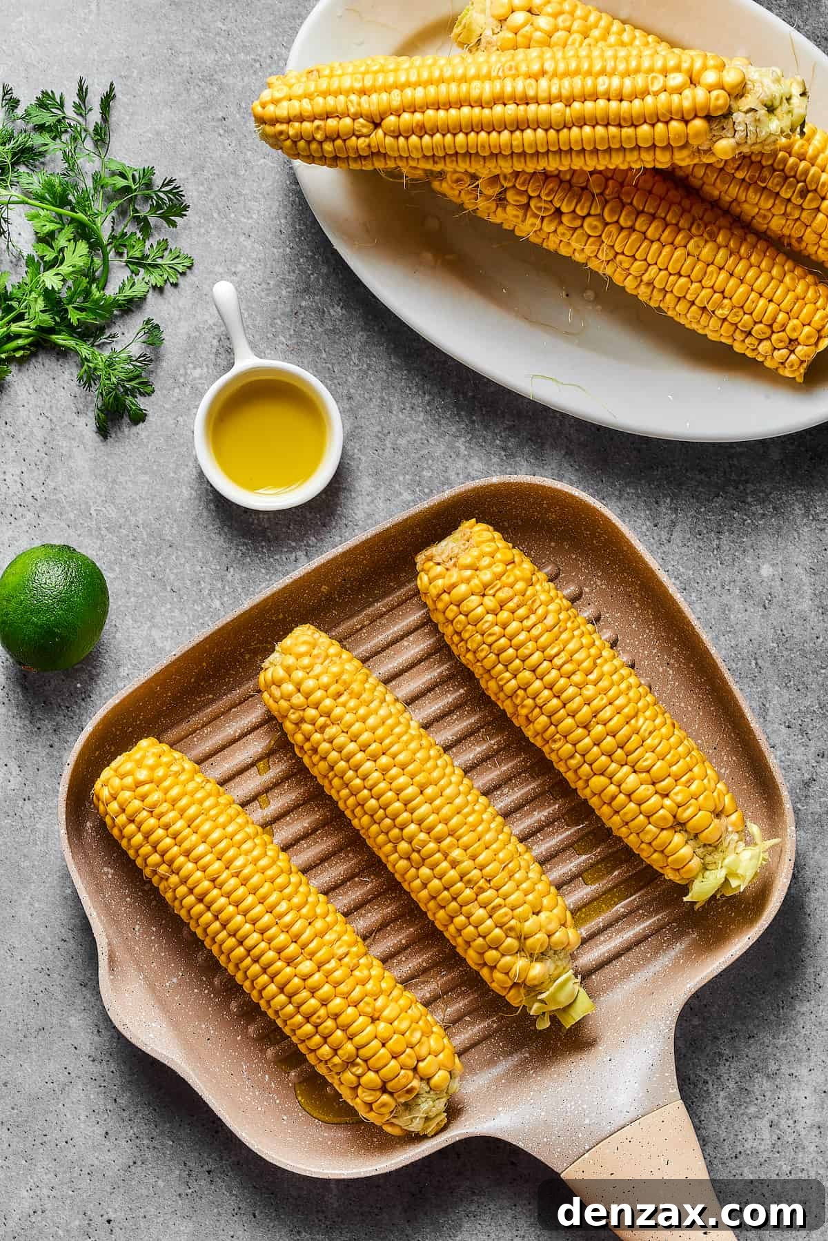 Ears of corn cooking on a grill pan, showing slight char marks developing.