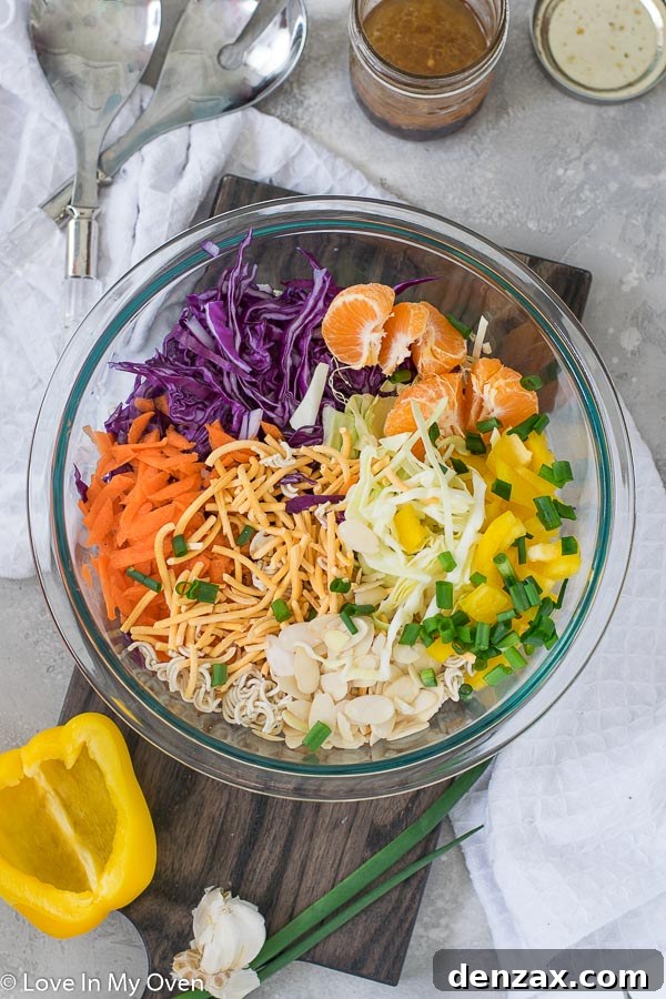 Mixing bowl with Crunchy Ramen Noodle Salad ingredients and a whisk for the dressing.