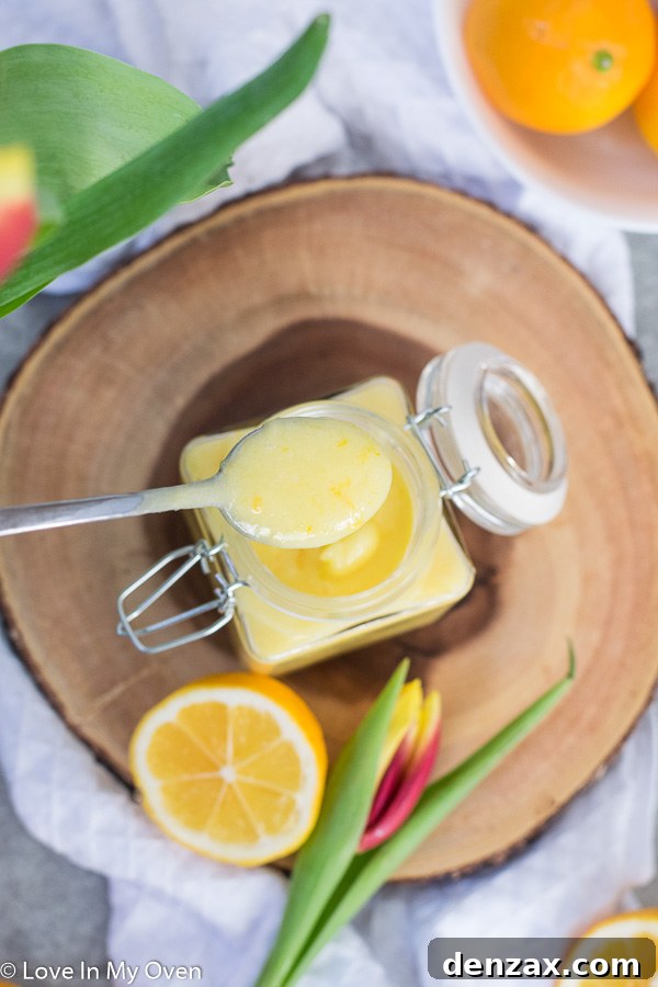 Close-up of Meyer lemon curd in a jar, with a spoon ready to scoop.