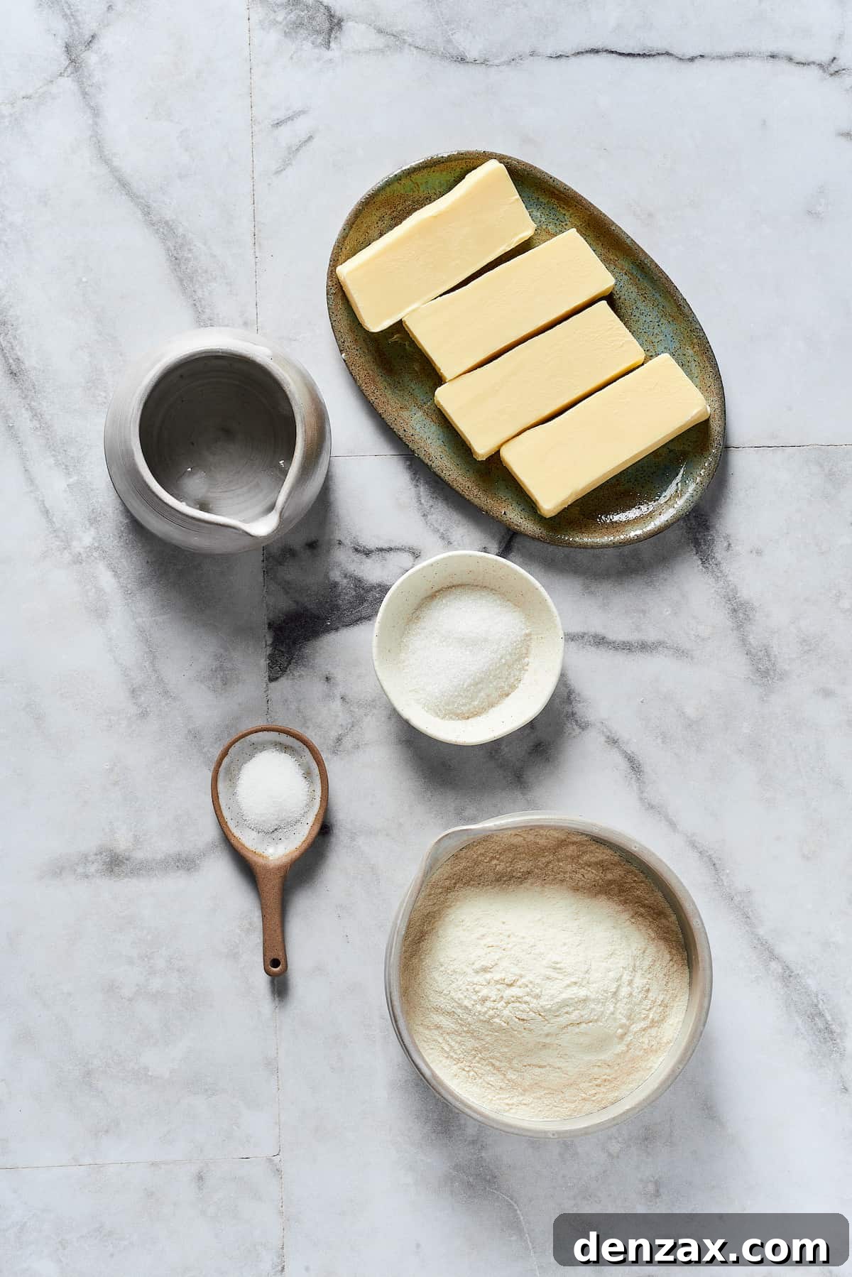 From Top: Diced cold butter, granulated sugar, all-purpose flour, sea salt, and a glass of ice water, showcasing the essential ingredients for a perfect pie crust.