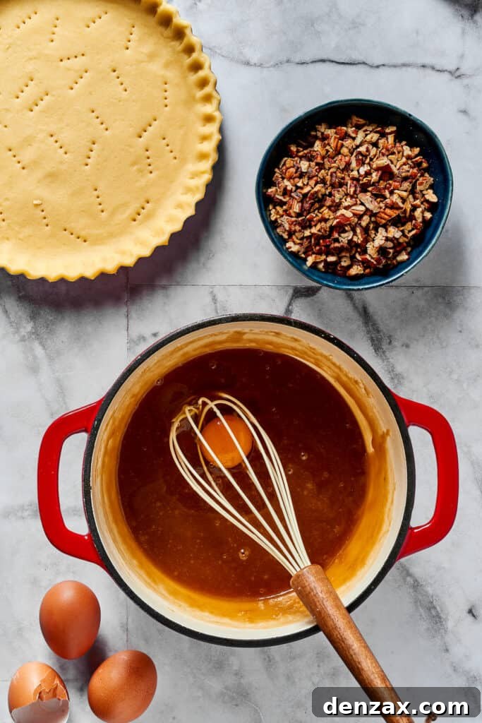 Irresistible Pecan Pie 4 The process of gently beating eggs into the cooled maple syrup mixture in a bowl, ensuring a smooth, emulsified filling for the pie.