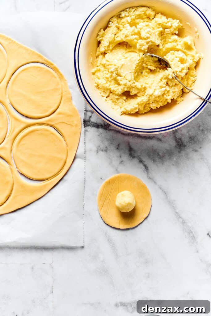 A single round of dough with a perfectly portioned ball of potato filling in its center, ready to be folded.